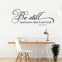 Load image into Gallery viewer, A wall decal with the text 'Be still and know that I am God. Psalm 46:10' displayed on a wall above a desk with a lamp and other office items.